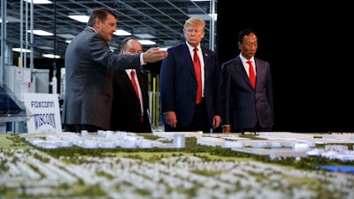 In this June 28, 2018 photo, President Donald Trump takes a tour with Foxconn chairman Terry Gou and CEO of SoftBank Masayoshi Son in Mt. Pleasant, Wis.