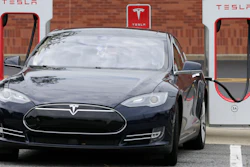 In this June 24, 2017, file photo, a Tesla Model 3 car recharges at at Cochran Commons shopping center in Charlotte, N.C.