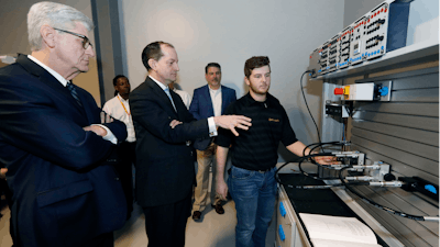 U.S. Secretary of Labor Alexander Acosta asks about the hydraulic maintenance and troubling shooting simulator with a student at the Continental Tire manufacturing plant, Friday, Feb. 8, 2019, in Clinton, Miss.
