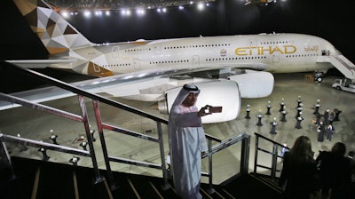 In this Dec. 18, 2014, file photo, a man takes a photo in front of a new Etihad Airways A380 in Abu Dhabi, United Arab Emirates.