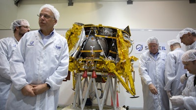 In this Monday, Dec. 17, 2018 file photo, technicians stand next to the SpaceIL lunar module in their facility near Tel Aviv, Israel.