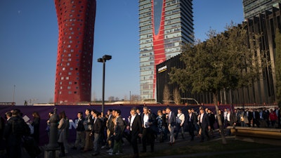 Attendees walk to enter the Mobile World Congress wireless show in Barcelona, Monday, Feb. 25, 2019.