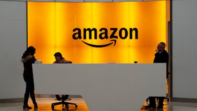 In this Feb. 14, 2019, file photo, people stand in the lobby for Amazon offices in New York.