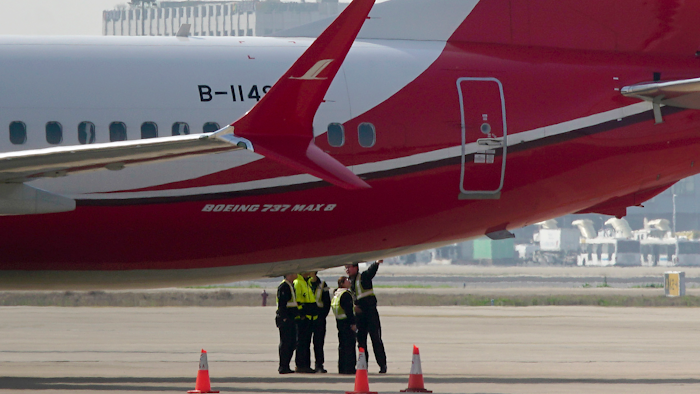 Ground crew chat near a Boeing 737 MAX 8 plane parked on the tarmac at Hongqiao airport in Shanghai, Tuesday, March 12, 2019.