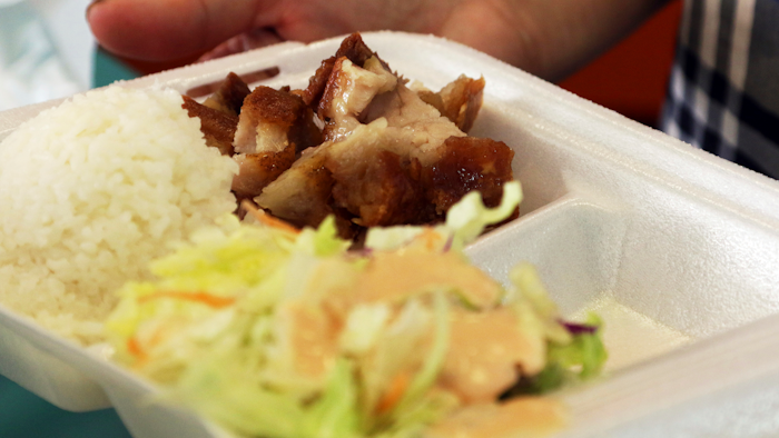 In this Thursday, March 14, 2019, photo, Belinda Lau, manager of the Wiki Wiki Drive Inn takeout restaurant in Honolulu, holds a polystyrene foam box containing an order of roast pork, rice and salad.