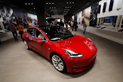In this Feb. 9, 2019, file photograph, buyers look over a Model 3 in a Tesla store in Cherry Creek Mall in Denver.