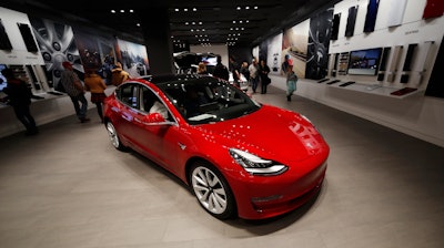 In this Feb. 9, 2019, file photograph, buyers look over a Model 3 in a Tesla store in Cherry Creek Mall in Denver.