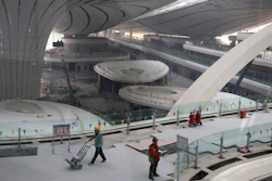 Workers pass through the terminal of the Beijing Daxing International Airport under construction on the outskirts of Beijing, Friday, March 1, 2019.