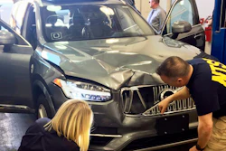 In this March 20, 2018, file photo, investigators examine a driverless Uber SUV that fatally struck a woman in Tempe, Ariz.