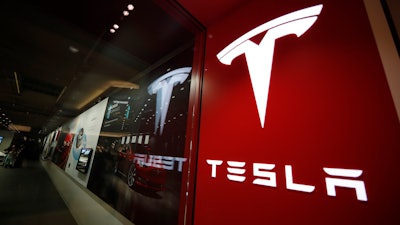 In this Feb. 9, 2019, file photo, a sign bearing the company logo is displayed outside a Tesla store in Cherry Creek Mall in Denver.