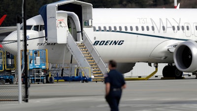 In this March 14, 2019, file photo, a worker walks next to a Boeing 737 MAX 8 airplane parked at Boeing Field in Seattle.