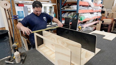 In this July 11, 2018, file photo, a worker assembles interior cabinets for a boat at Regal Marine Industries in Orlando, Fla.