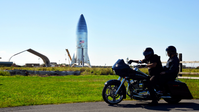 In this Jan. 12, 2019 file photo, a motorcyclist rides near the SpaceX prototype at the Boca Chica Beach site in Texas.