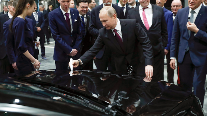 Russian President Vladimir Putin signs a car hood during an opening ceremony of the Mercedes Benz automobile assembly plant outside Moscow, Wednesday, April 3, 2019.