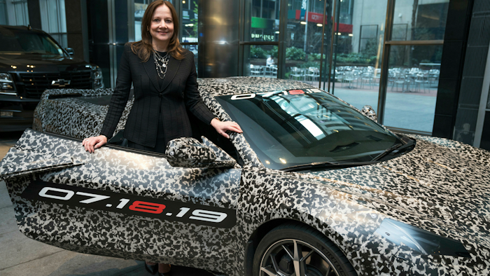 GM chairman and CEO Mary Barra standing by a camouflaged next generation Chevrolet Corvette Thursday, April 11, 2019, in New York.
