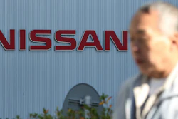 In this Jan. 9, 2019, photo, a man walks past the logo at global headquarters of Nissan Motor Co. in Yokohama.