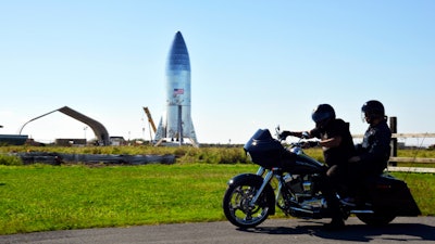 In this Jan. 12, 2019 file photo, a motorcyclist rides near the SpaceX prototype at the Boca Chica Beach site in Texas.