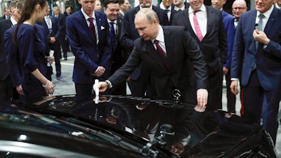 Russian President Vladimir Putin signs a car hood during an opening ceremony of the Mercedes Benz automobile assembly plant outside Moscow, Wednesday, April 3, 2019.