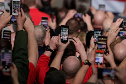 In this March 20, 2019, photo, workers take photos with their phones as President Donald Trump speaks at Joint Systems Manufacturing Center in Lima, Ohio.
