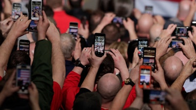 In this March 20, 2019, photo, workers take photos with their phones as President Donald Trump speaks at Joint Systems Manufacturing Center in Lima, Ohio.
