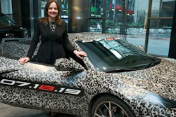 GM chairman and CEO Mary Barra standing by a camouflaged next generation Chevrolet Corvette Thursday, April 11, 2019, in New York.