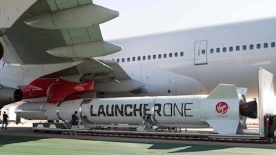 In this Thursday, Oct. 25, 2018, photo, a LauncherOne rocket hangs from the wing of Cosmic Girl, a special Boeing 747 aircraft that is used as the rocket's 'flying launch pad.'