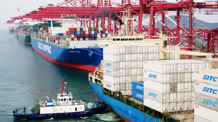 In this Wednesday, May 8, 2019, photo, a barge pushes a container ship to the dockyard in Qingdao in eastern China's Shandong province.