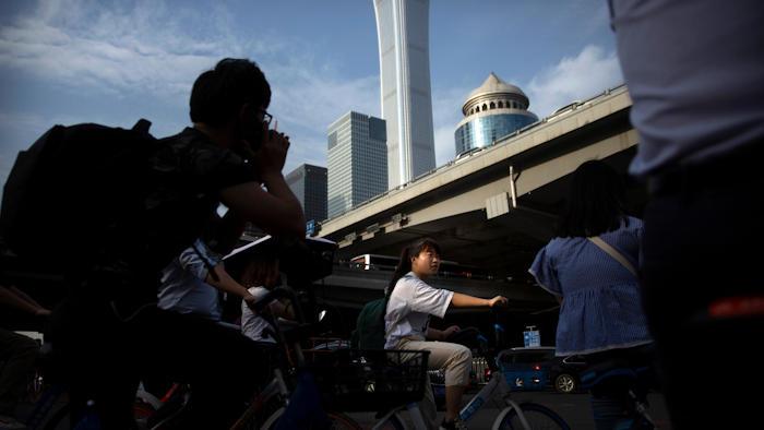 People wait cross the street in a crosswalk in the central business district in Beijing, Friday, May 24, 2019.