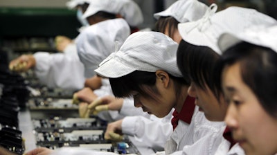 In this Wednesday, May 26, 2010, file photo, staff members work on the production line at the Foxconn complex in Shenzhen, China.