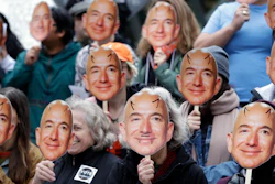 In this Oct. 31, 2018, file photo, demonstrators hold images of Amazon CEO Jeff Bezos near their faces during a protest over the company's 'Rekognition' facial recognition system.