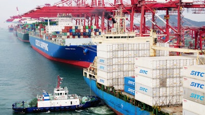 In this Wednesday, May 8, 2019, photo, a barge pushes a container ship to the dockyard in Qingdao in eastern China's Shandong province.