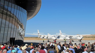 In this Oct. 17, 2011, file photo, a crowd gathers outside Spaceport America near Upham, N.M., for a dedication ceremony as Virgin Galactic's WhiteKnightTwo sits on the tarmac.