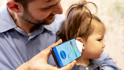 Dr. Randall Bly uses a uses a phone app and a paper funnel, to focus the sound, to check his daughter for an ear infection at the UW School of Medicine in Seattle.