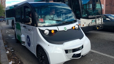 An autonomous shuttle bus, foreground, is seen Wednesday, May 15, 2019, in Olneyville Square in Providence, R.I.