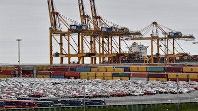 Cars for export and import are stored in front of containers on Thursday, May 16, 2019, at the harbor in Bremerhaven, Germany.