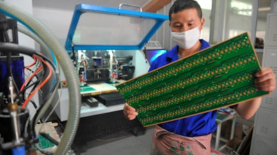 In this May 22, 2018, file photo, a staff member works in a circuit board manufacturing facility in Hangzhou in eastern China's Zhejiang province.