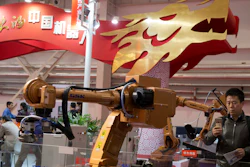 In this Friday, Oct. 21, 2016 photo, visitors look at industrial robots displayed during the World Robot Conference in Beijing.