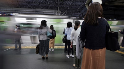 Commuters wait to get on a train at a station Wednesday, May 22, 2019, in Tokyo.