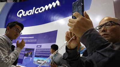 In this Nov. 6, 2018, file photo, attendees look at the latest technology from Qualcomm at the China International Import Expo in Shanghai.