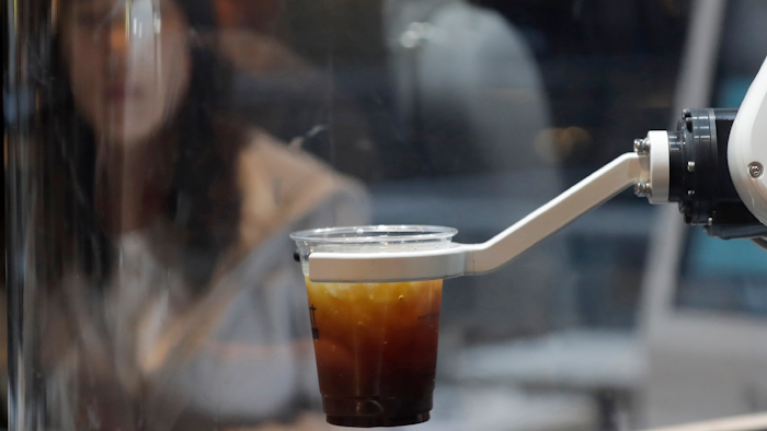 In this May 22, 2019, photo, a customer waits for a coffee in front of a robot named b;eat after placing an order at a cafe in Seoul.