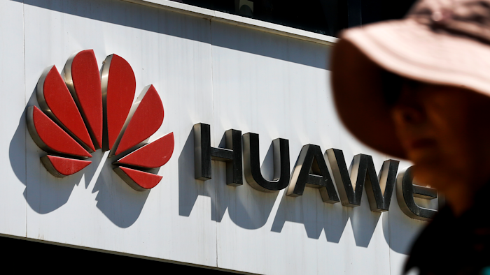 In this May 29, 2019, file photo, a woman walks by a Huawei retail store in Beijing.