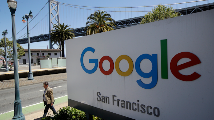 In this May 1, 2019, file photo, a man walks past a Google sign with a span of the Bay Bridge at rear in San Francisco.