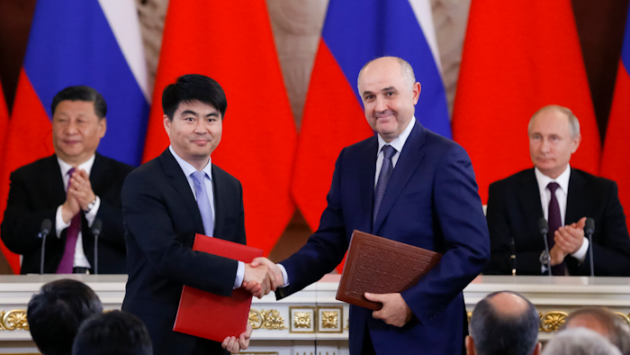 Guo Ping, deputy Chairman of Huawei Technologies Co Ltd, foreground left, shakes hands with Russian President of MTS mobile network operator, Alexei Kornya as Russian President Vladimir Putin, right, and Chinese President Xi Jinping attend a signing ceremony following their talks in the Kremlin in Moscow, Russia, Wednesday, June 5, 2019. Chinese President Xi Jinping is on visit to Russia this week and is expected to attend Russia's main economic conference in St. Petersburg.