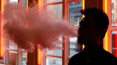 In this Feb. 20, 2014, file photo, a customer exhales vapor from an e-cigarette at a store in New York.