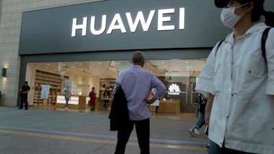 In this photo taken Monday, May 20, 2019, a man stands outside a Huawei store in Beijing.