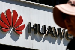 In this May 29, 2019, file photo, a woman walks by a Huawei retail store in Beijing.