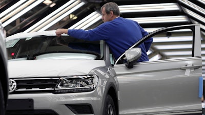 In this Thursday, March 8, 2018, photo, an employee works on a car during a final quality control at the Volkswagen plant in Wolfsburg, Germany.