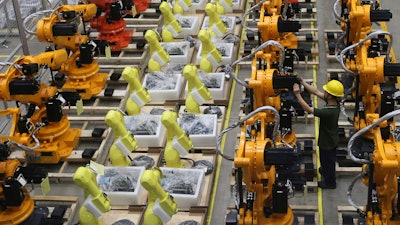 A worker checks on robot arms at a factory in Nanjing in east China's Jiangsu province, Thursday, June 6, 2019.