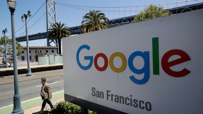 In this May 1, 2019, file photo, a man walks past a Google sign with a span of the Bay Bridge at rear in San Francisco.