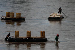Men use rafts to transport black-market gasoline across the Suchiate River from Guatemala to Mexico, as one pushes sacks of corn in the opposite direction to Guatemala, near Ciudad Hidalgo, Mexico, Thursday, June 6, 2019.